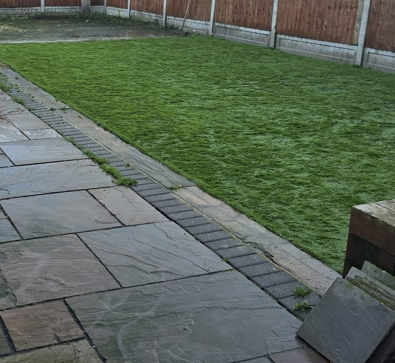 Clean, striped artificial grass bordering a paved patio in an Essex garden