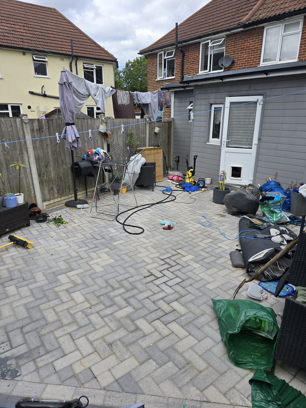 Cluttered, mossy block paving patio before a garden clearance and pressure wash