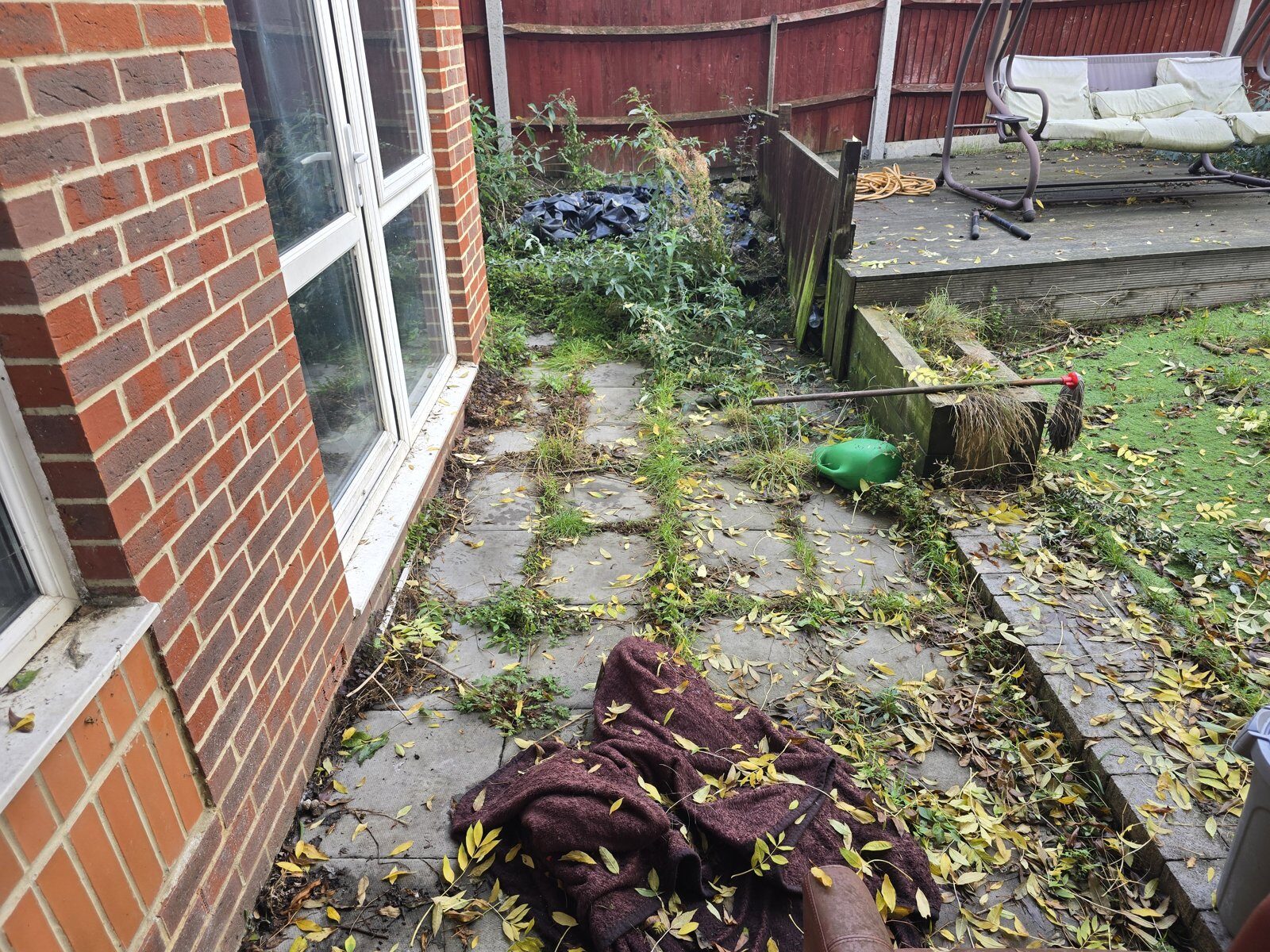 Overgrown, leaf-covered patio slabs before cleaning